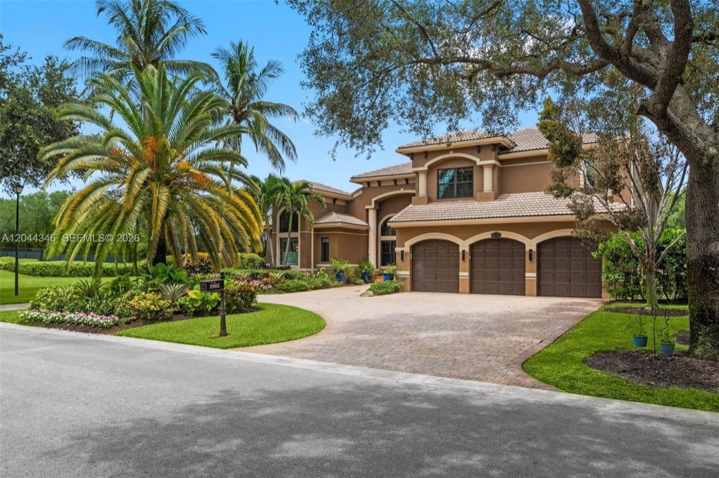 Daytime three-quarter view of the estate's full facade with a three-car garage and columned front entry